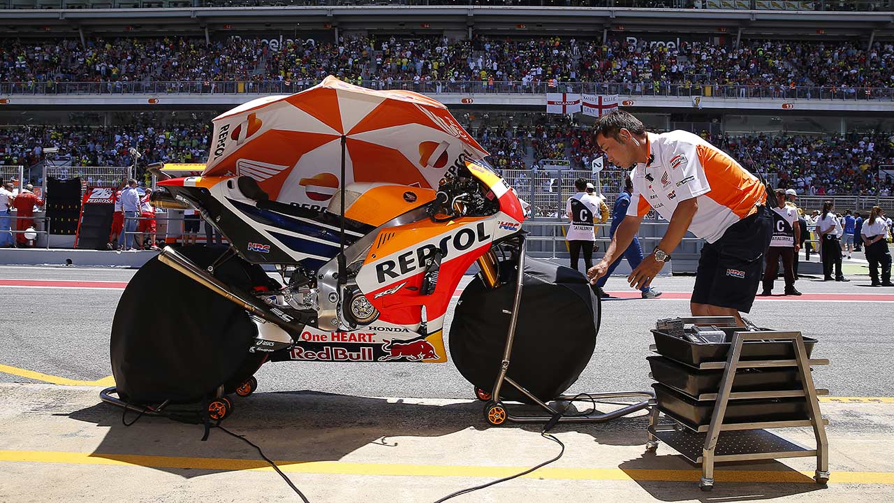 Mecánico junto a moto con calentadores de neumáticos de motogp en el pitlane