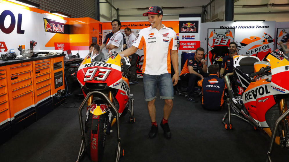 Marc Márquez smiles next to his bike