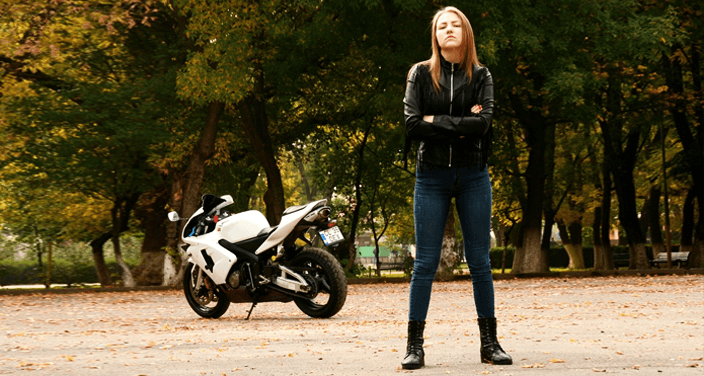 Chica con cazadora motera posando frente a moto blanca
