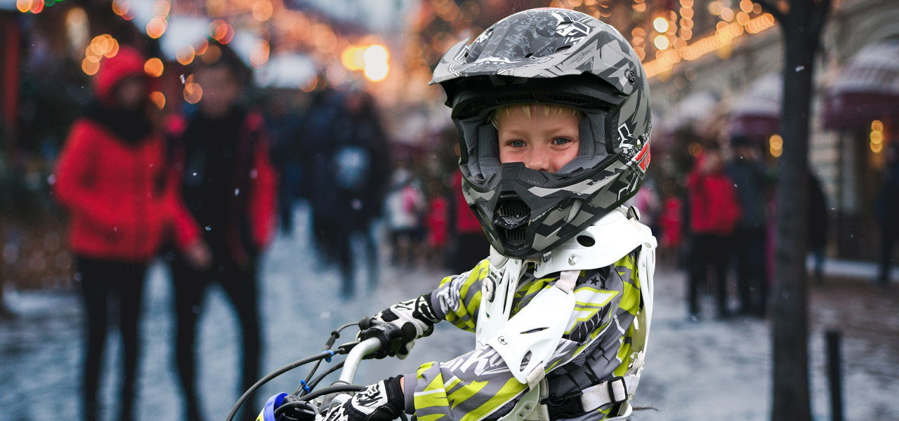 Niño con casco y mono de motocross en un ambiente navideño