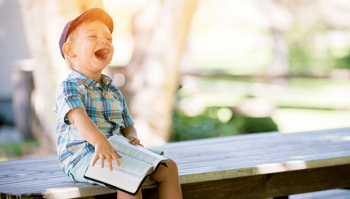 Niño sentado, riendo con un libro Niño sentado, riendo con un libro