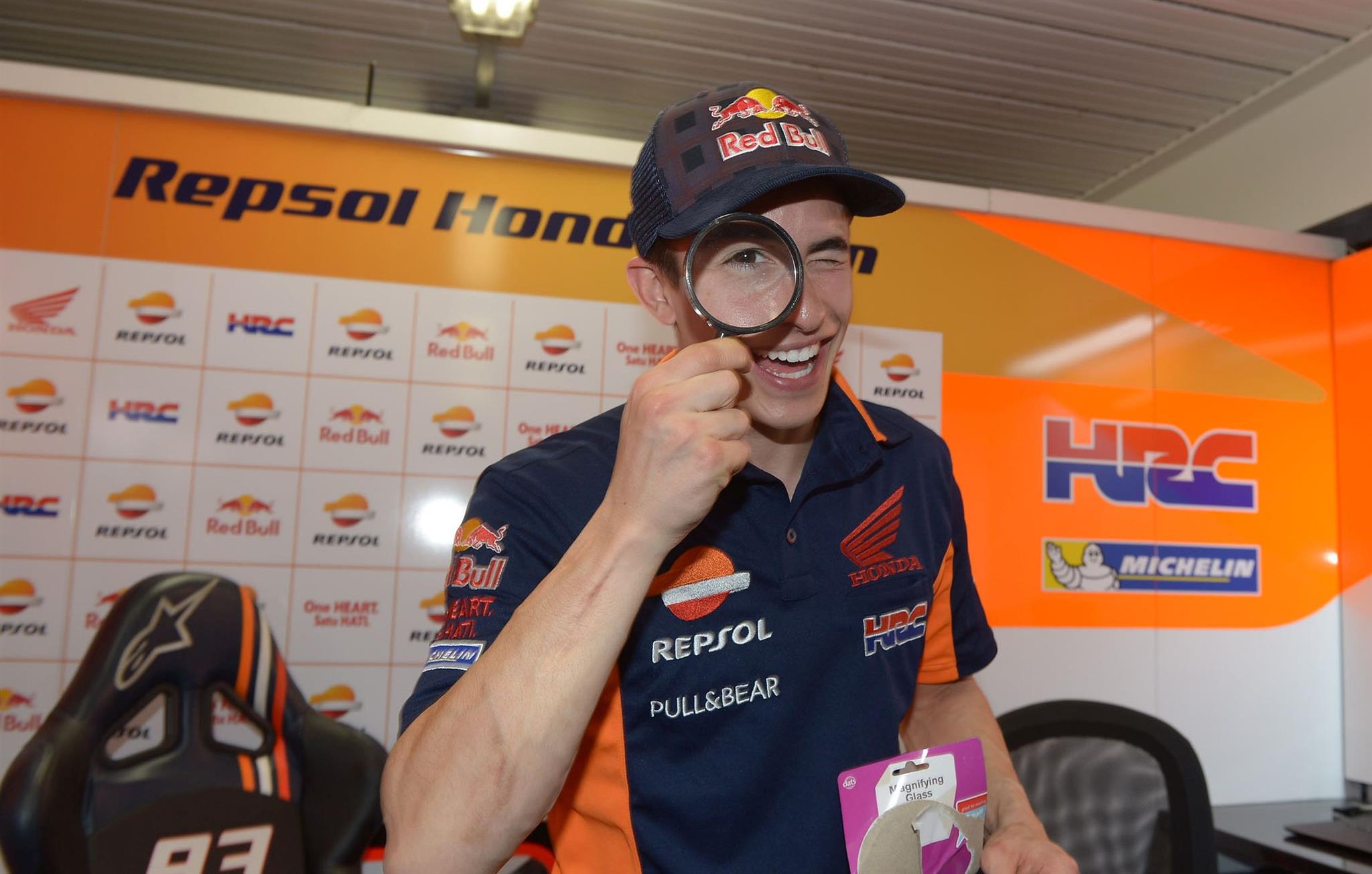 Marc Márquez mirando a través de una lupa que le regaló su equipo en su cumpleaños