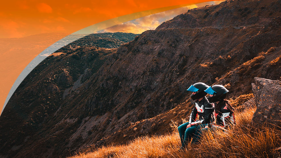 Pareja motera en la naturaleza, en la ladera de una montaña cerca de la carretera