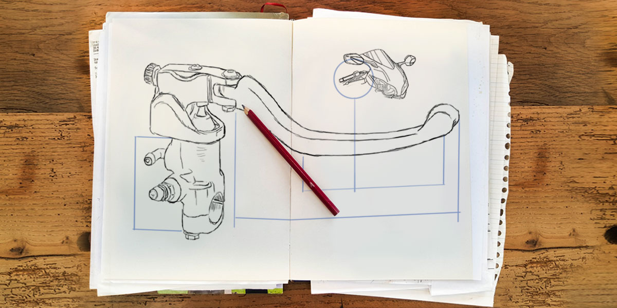 Esbozo a lápiz de una maneta de freno con bomba radial en papel sobre una mesa de madera