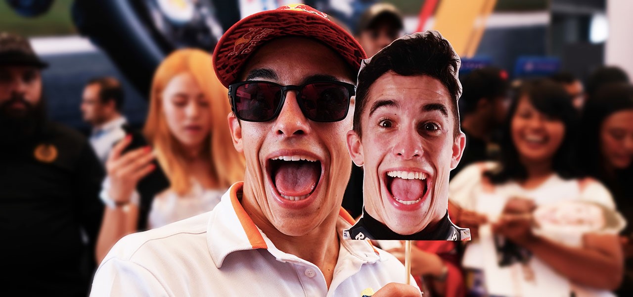 Marc Márquez con gafas de soly gorra de Repsol se divierte imitando la cara de una careta que está sosteniendo