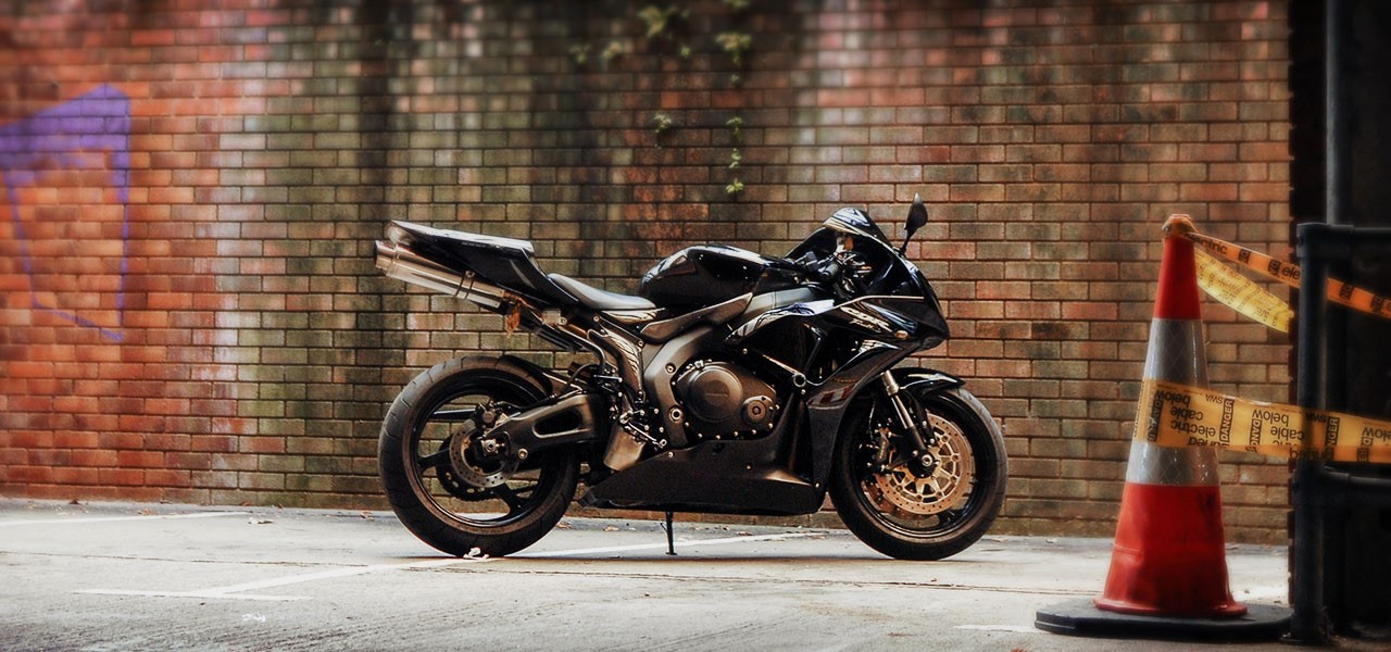 Moto Honda negra en frente de un muro de ladrillo