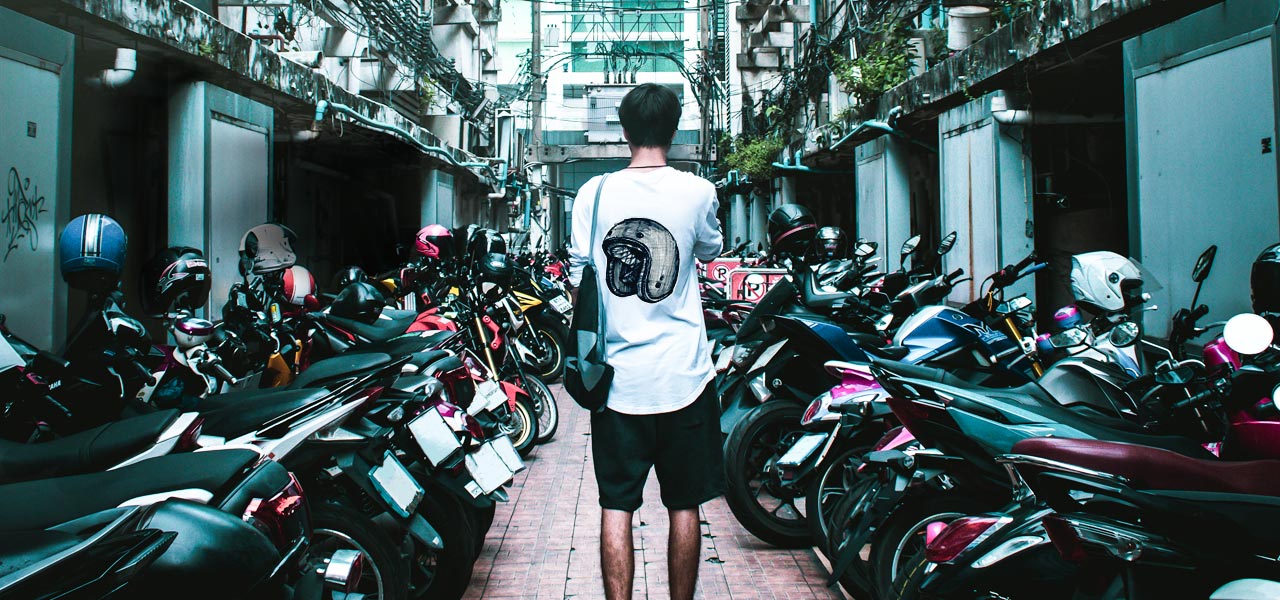 motero sin moto de espaldas rodeado de gran cantidad de motos aparcadas