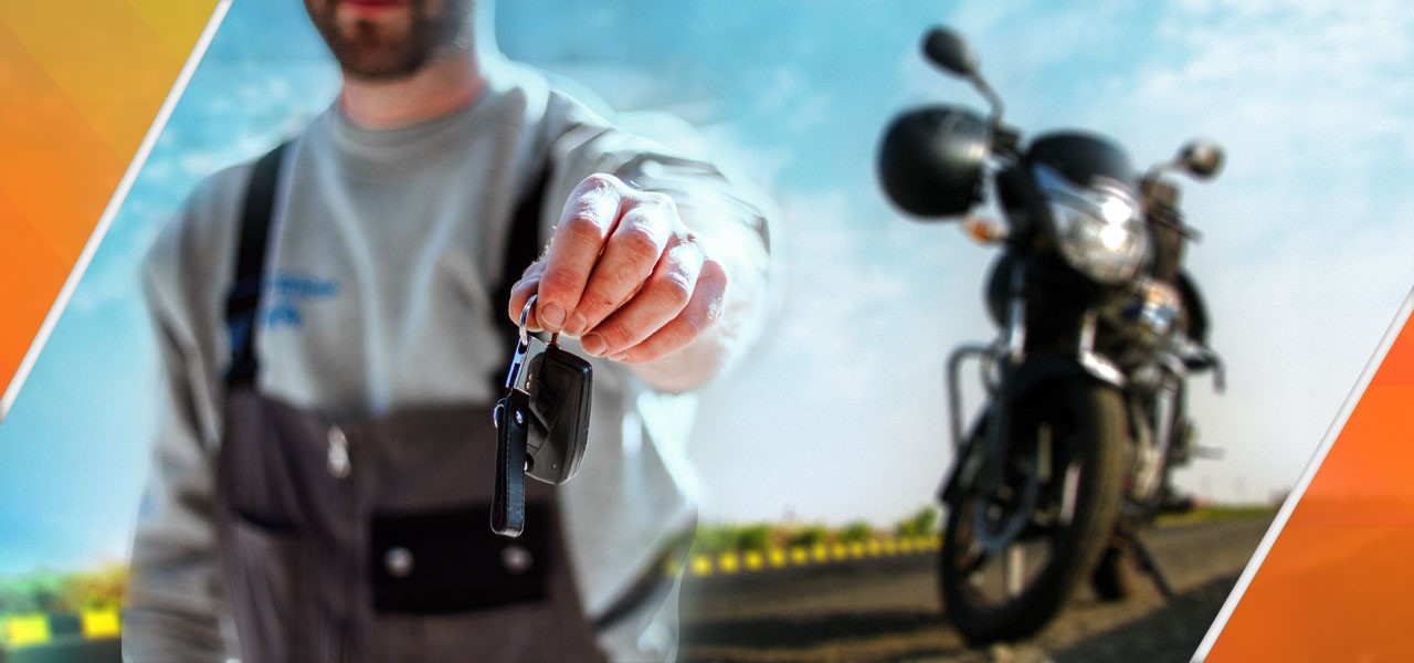 hombre con el brazo extendido ofrece a cámara las llaves de una moto naked que vemos aparcada en segundo plano