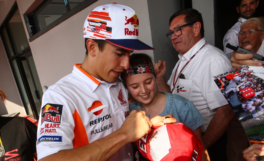 Marc Márquez firma la gorra a una fna en un Gran Premio de MotoGP