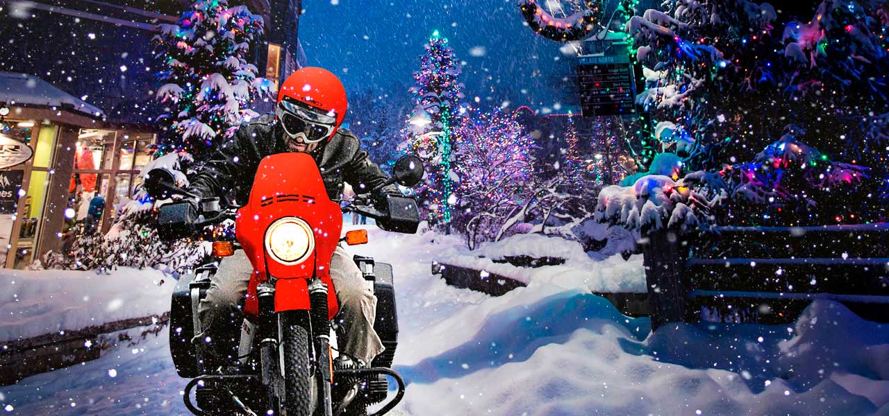 Motero conduce su moto navidenya en medio de una ciudad nevada
