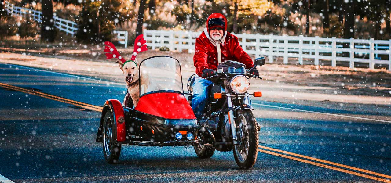 Un sidecar rojo conducido por papa noel y que lleva a un perro rudolf en la cesta