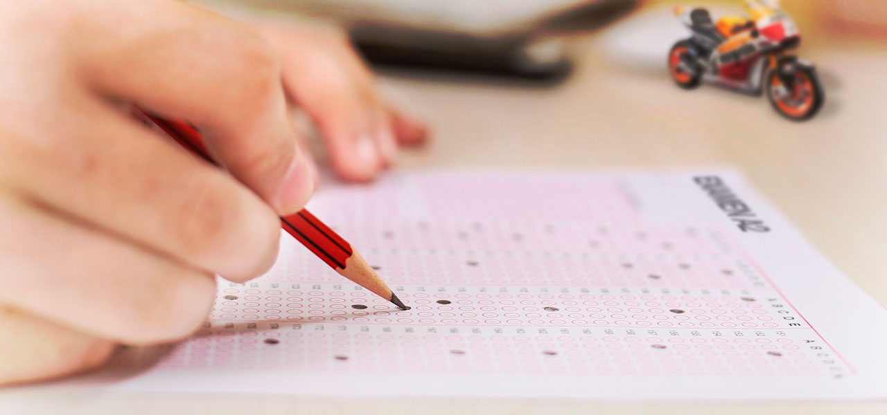 primer plano de la mana de un motero rellenando las casillas de un examen tipo test para sacarse el A2