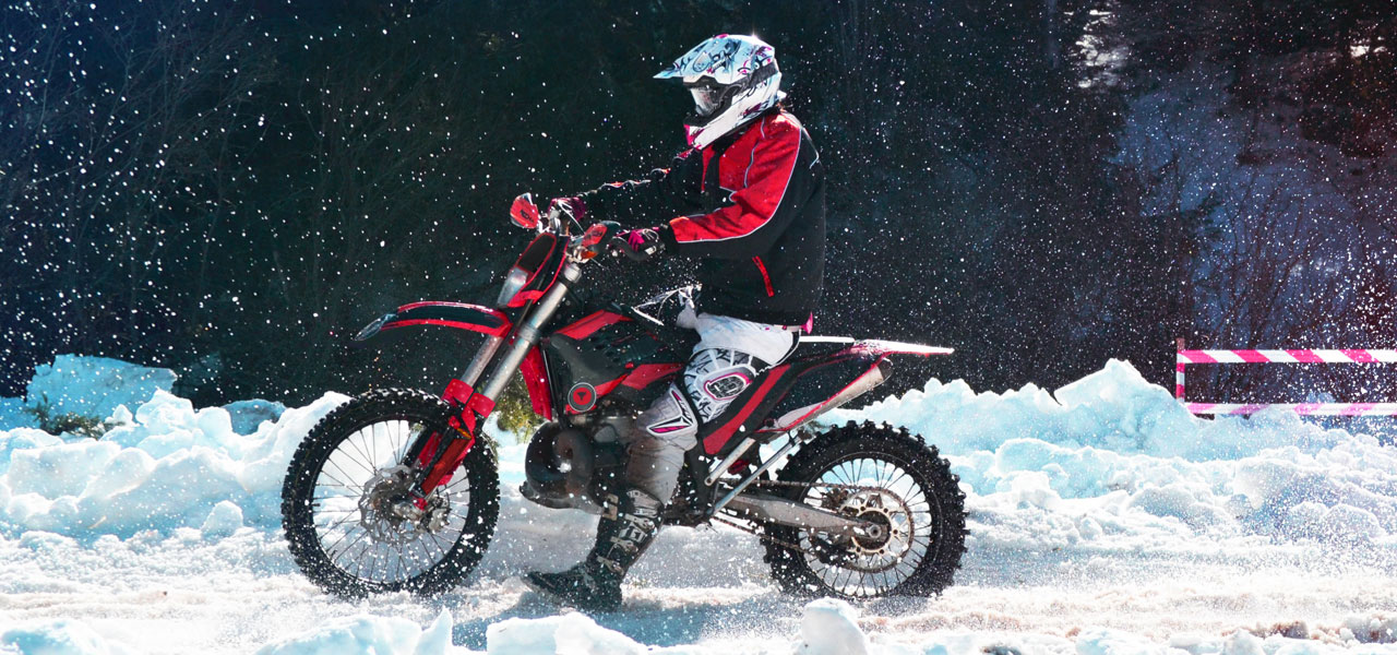 Piloto participando en una carrera de motos off road en la nieve