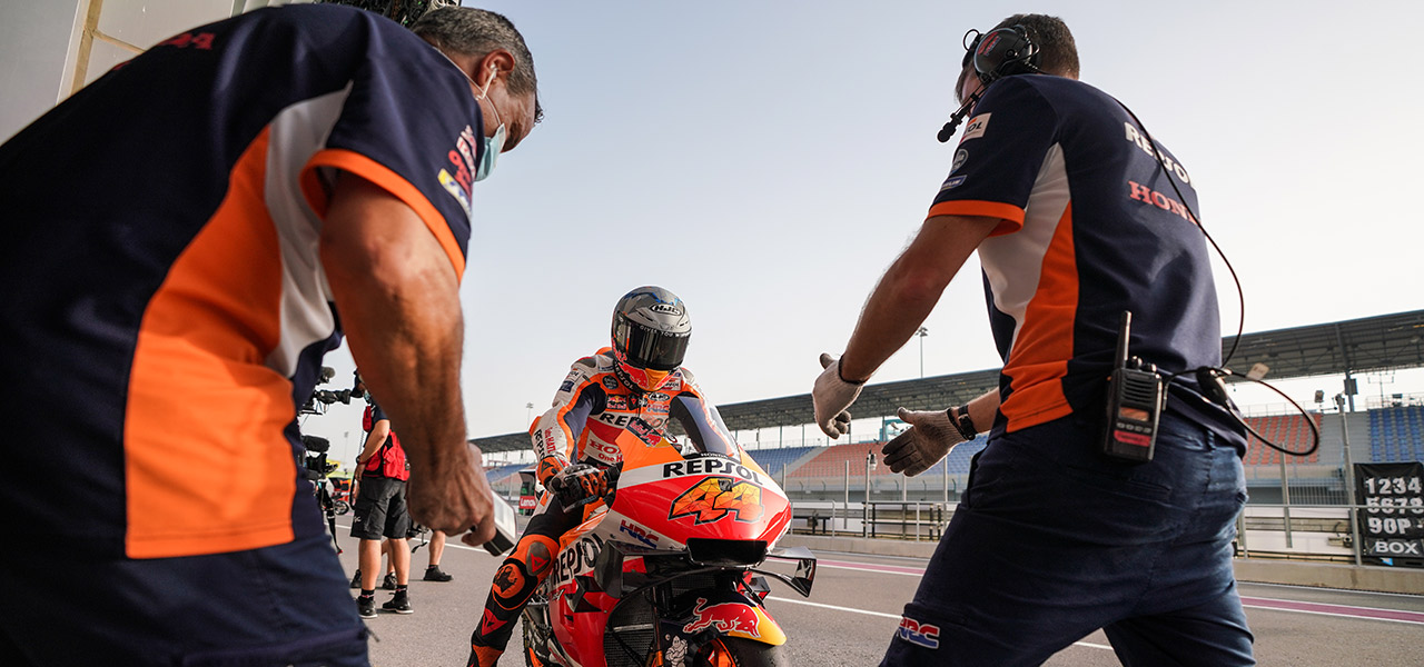 Pol Espargaró en el pitlane con dos mecánicos del equipo preparados para su llegada.