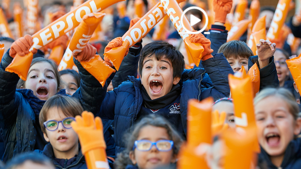 Niño animando con hinchables de Repsol y guantes naranjas