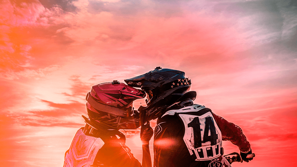 Moteros con cascos puestos en actitud romántica en puesta de sol